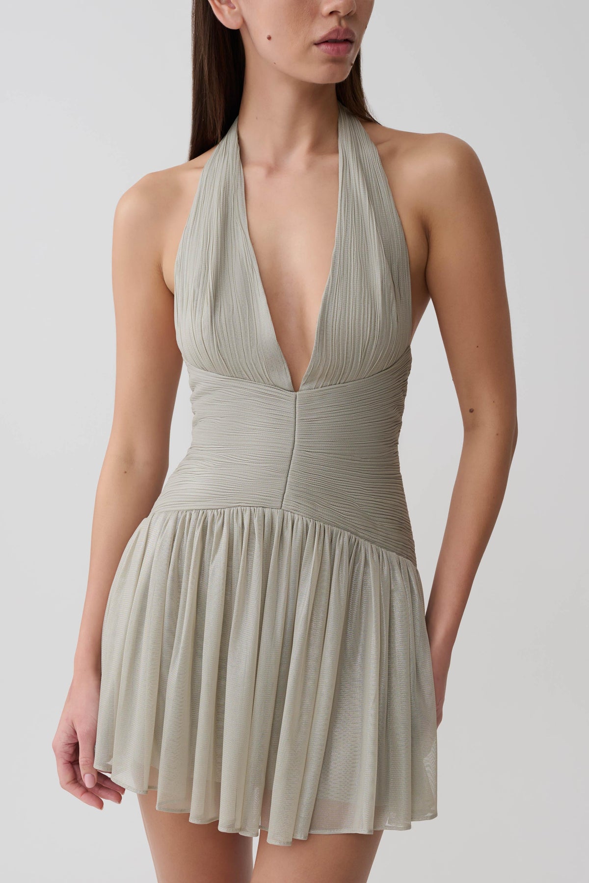 Womn wearing a silver halter pleated mini dress.