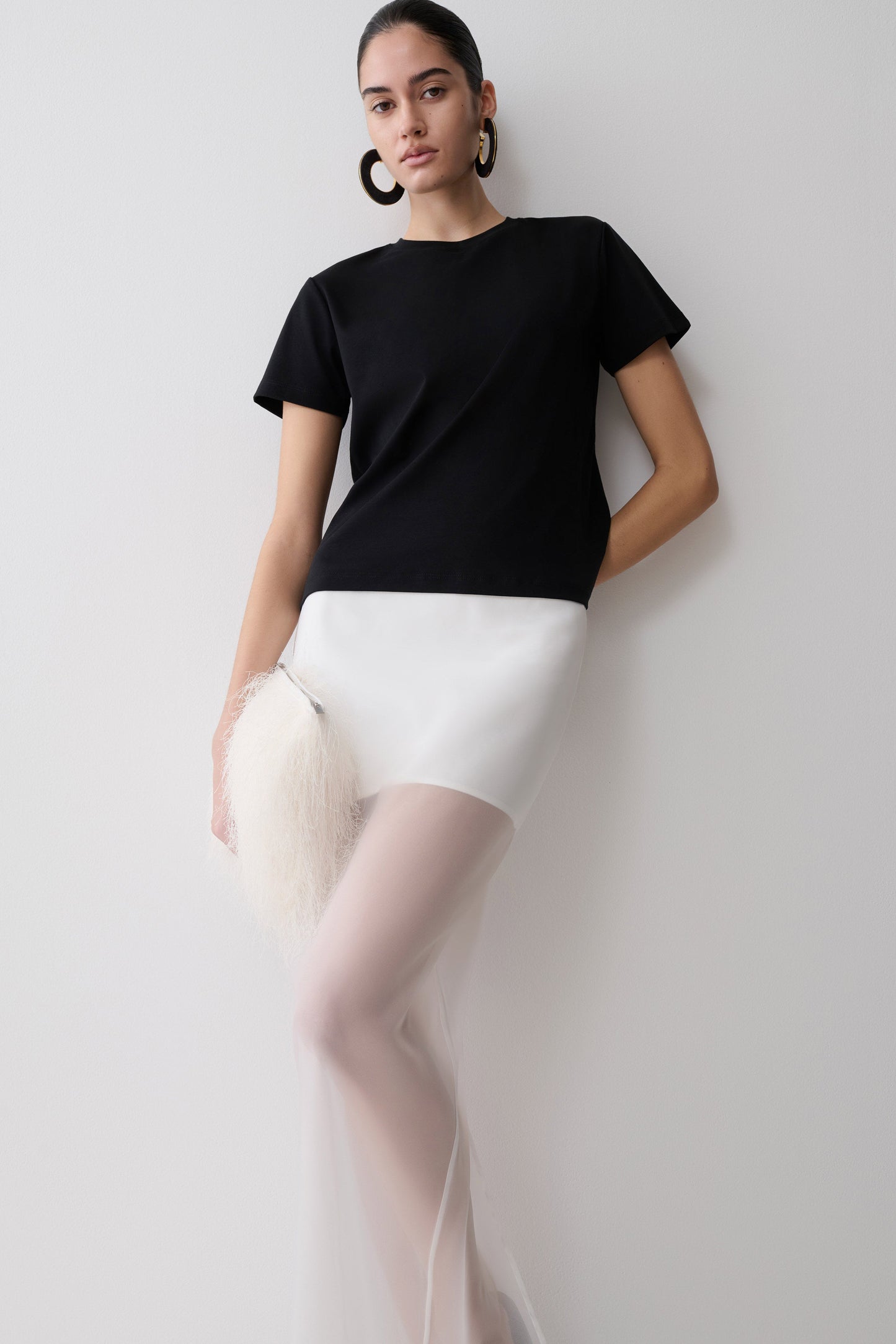 Woman wearing a black t-shirt and white organza maxi skirt.