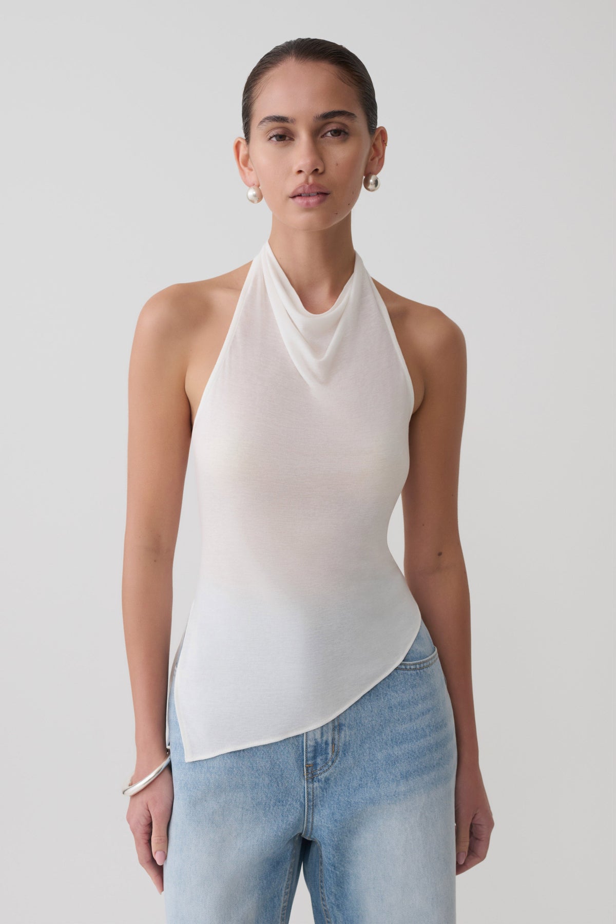 Woman wearing a white relaxed sheer halter top.