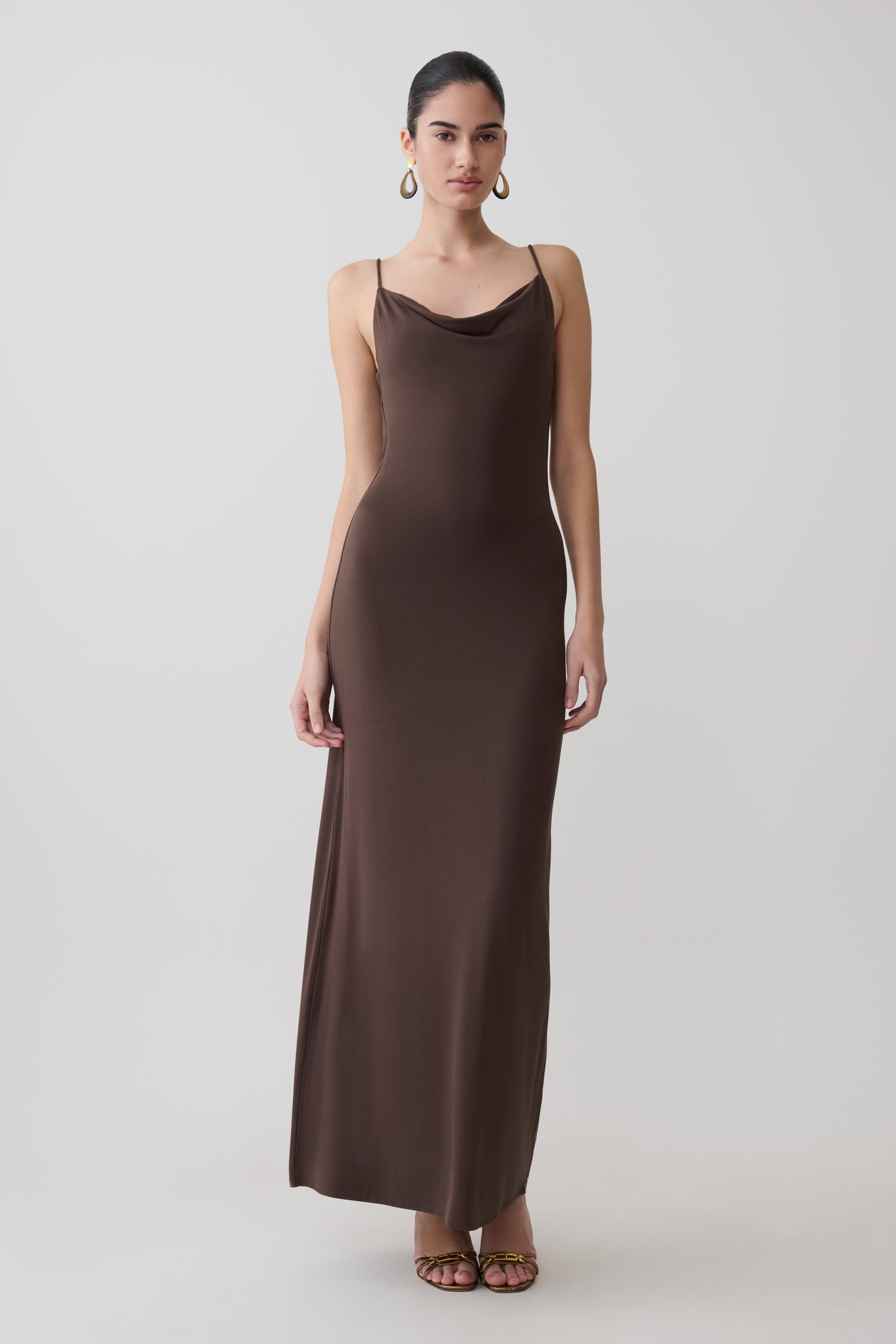 Woman wearing a dark chocolate cowl maxi dress.