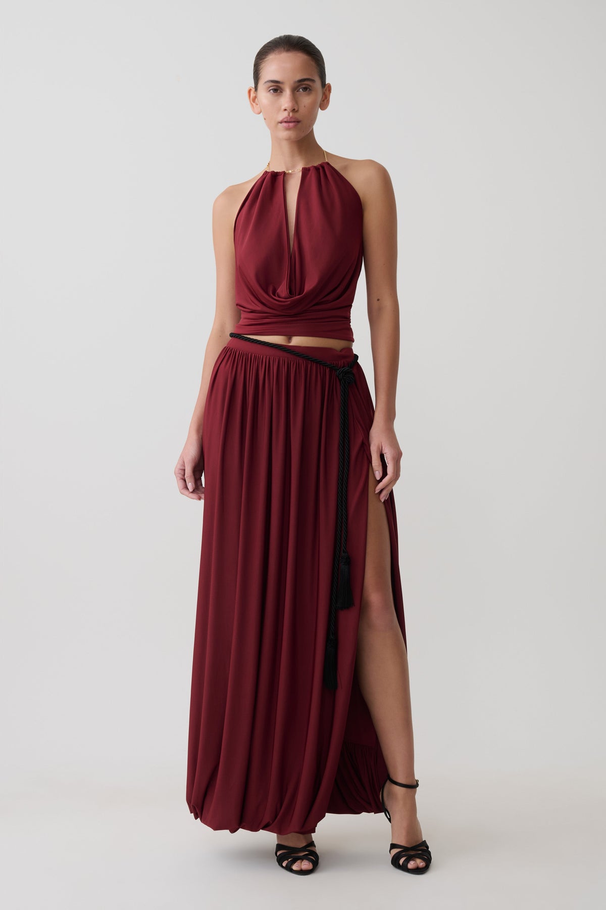 Woman wearing a dark red halter neck top with matching bubble hem midi skirt.