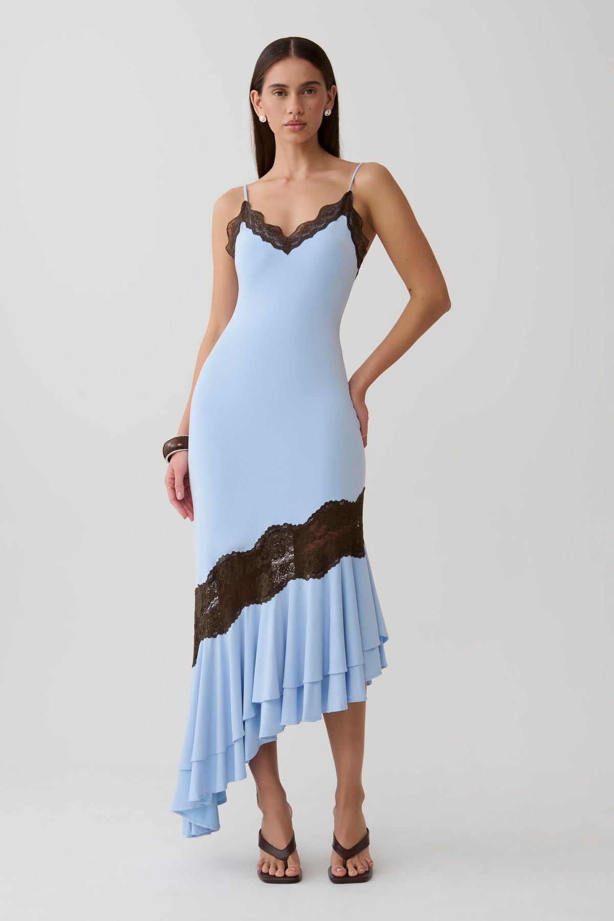 Woman wearing a blue and brown frilled hem lace midi dress.