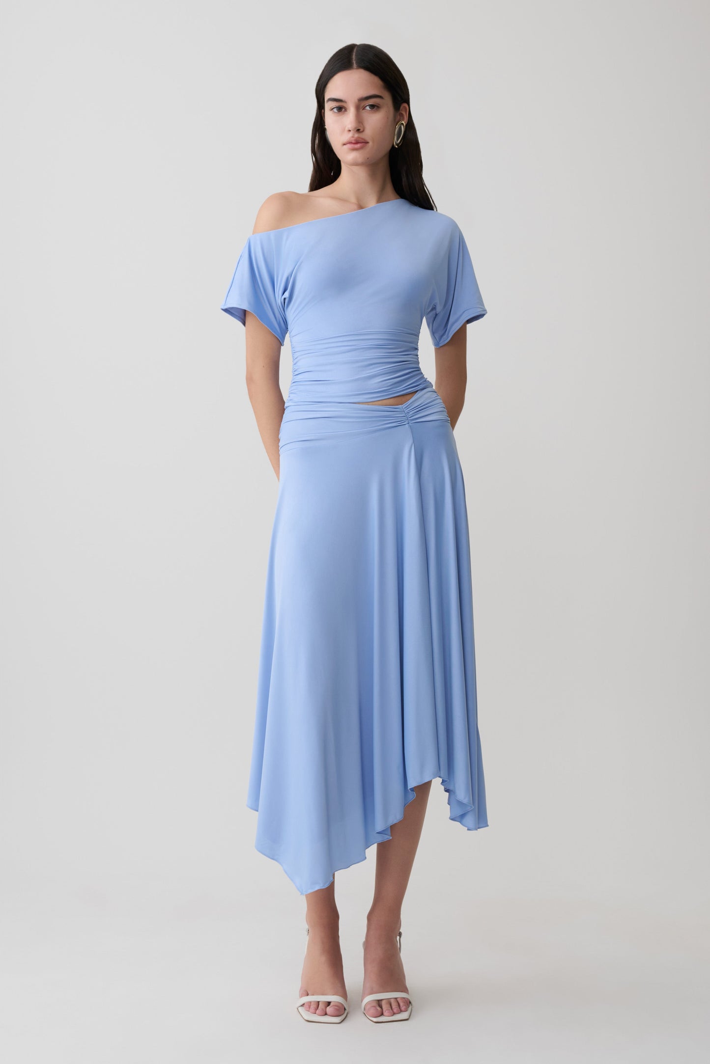 Woman wearing a blue off shoulder slinky top with matching midi skirt.