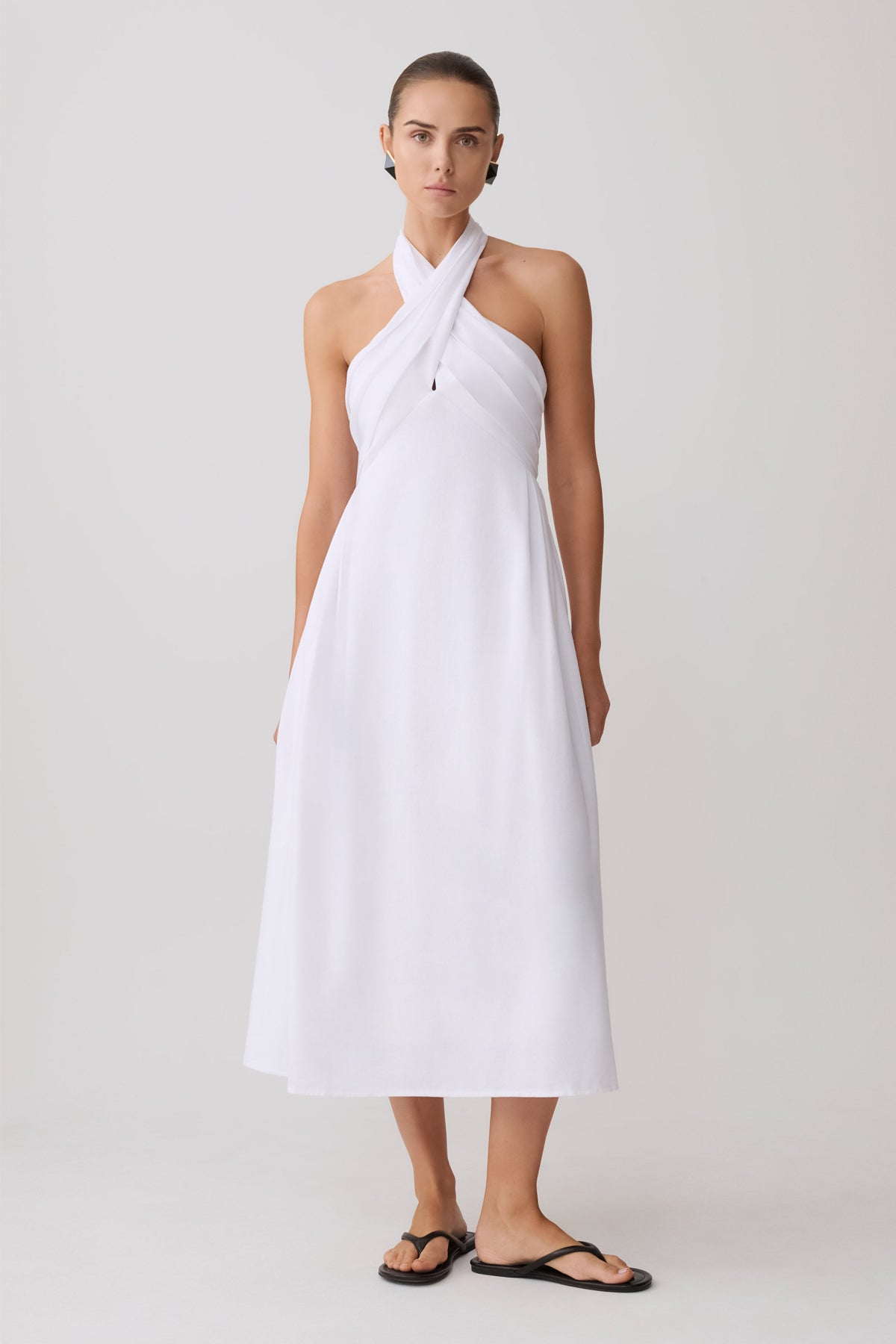Woman wearing a white halter neck maxi dress.
