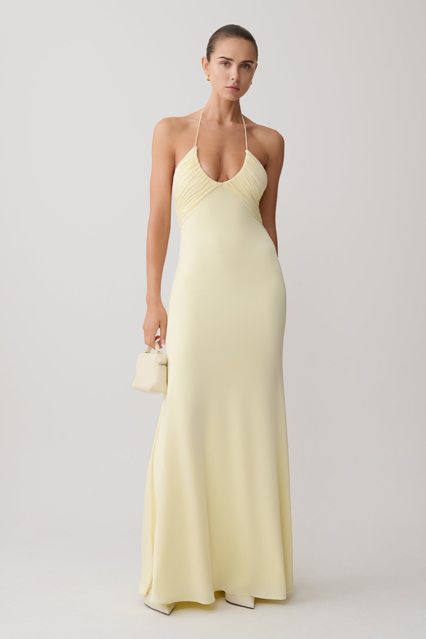 Woman wearing a light yellow halter neck maxi dress.