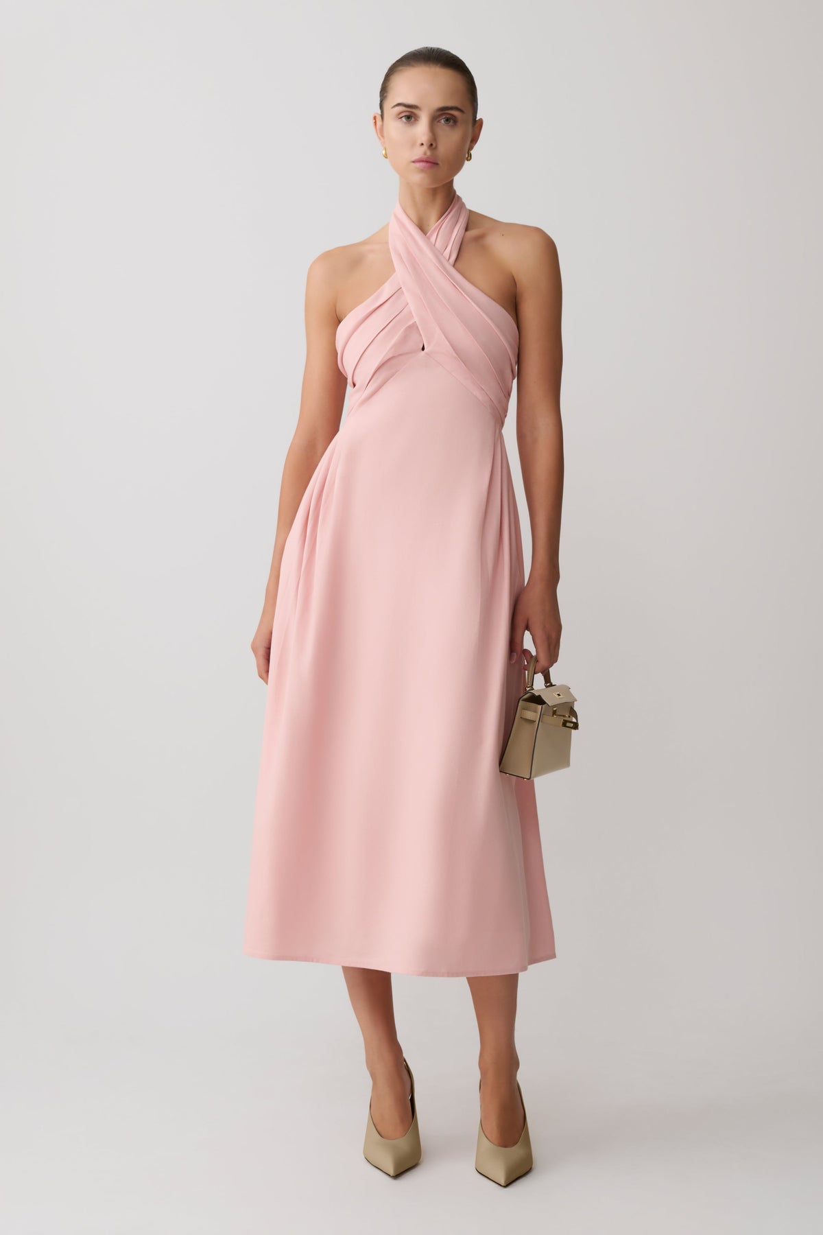 Woman wearing a pink croos over hallter maxi dress.