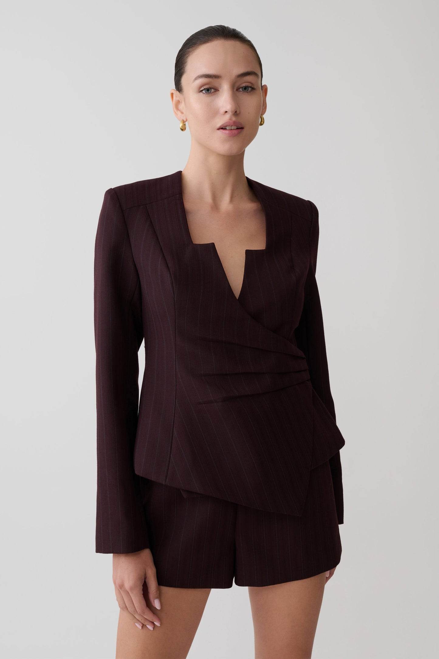 Woman wearing a dark brown striped blazer and shorts set.