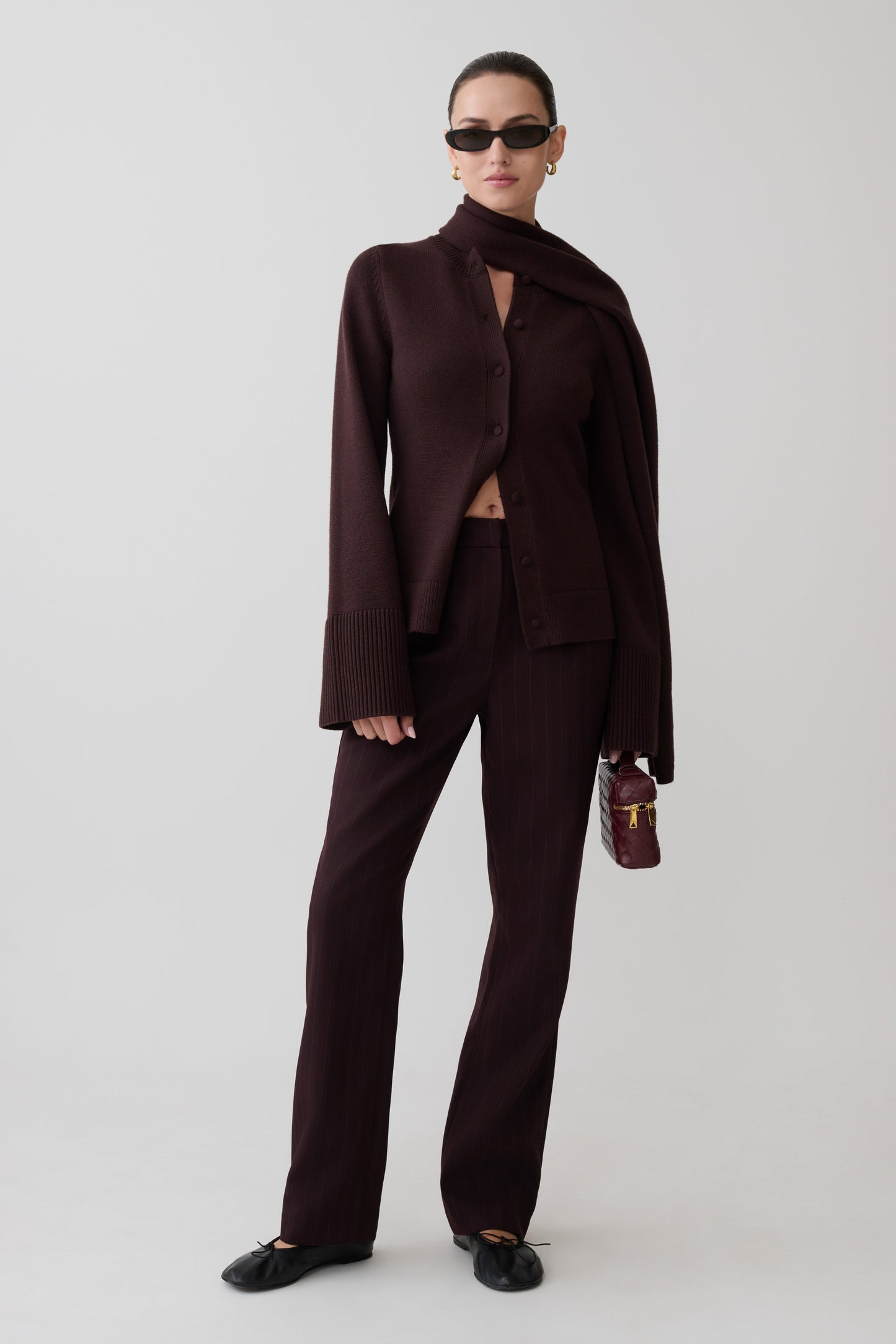 Woman wearing a dark brown cardigan with scarf.