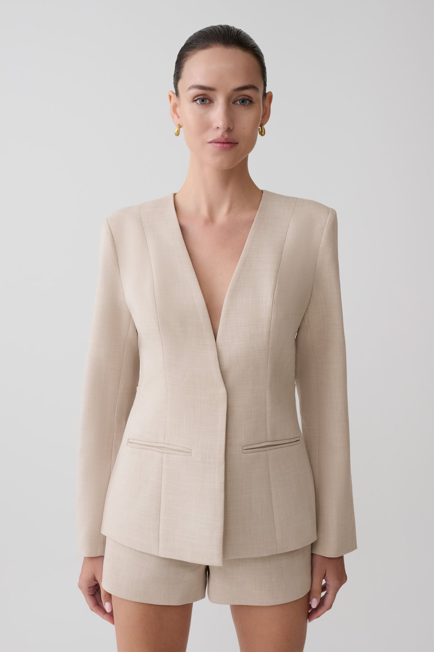 Woman wearing a beige blazer and matching shorts.