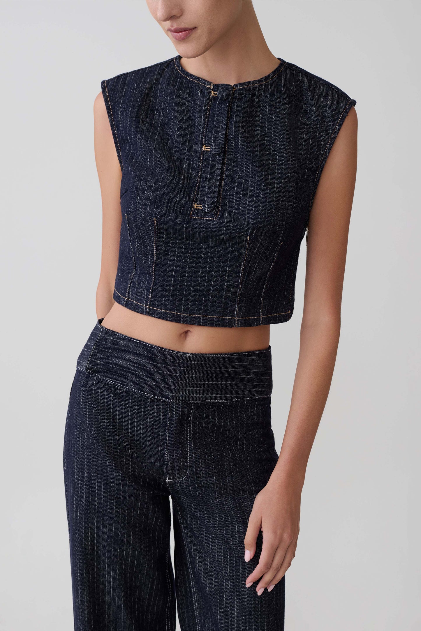 Woman wearing a dark blue sleeveless top and jeans.