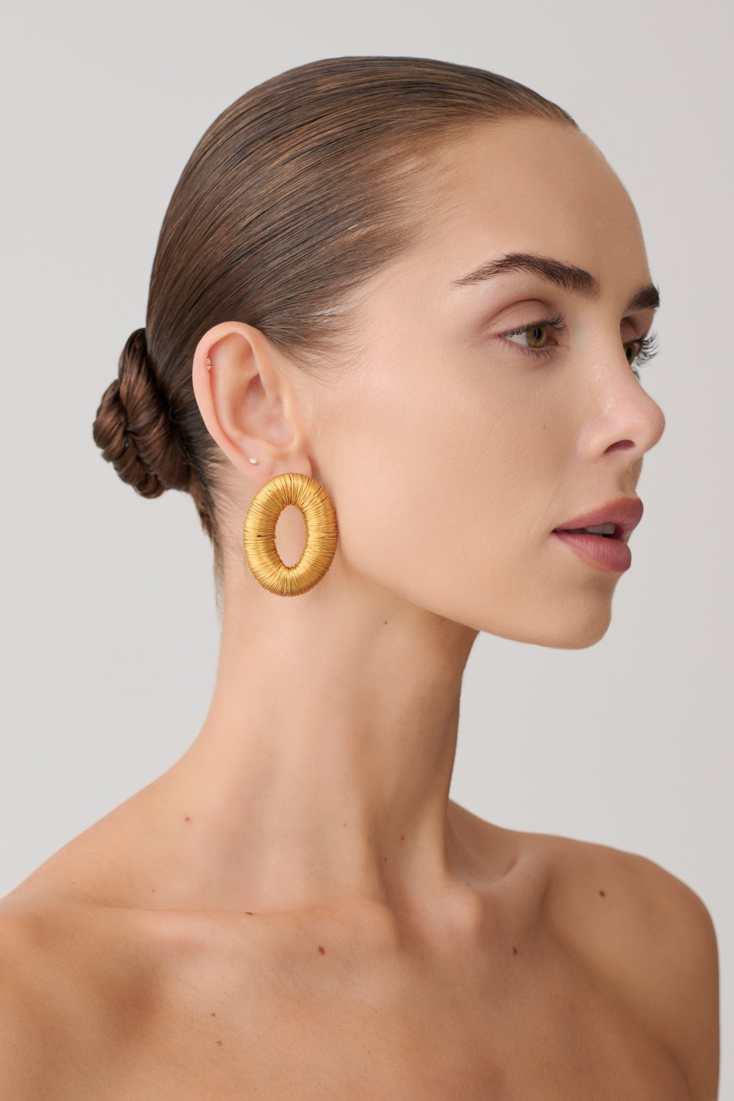Woman wearing round gold studded earrings.