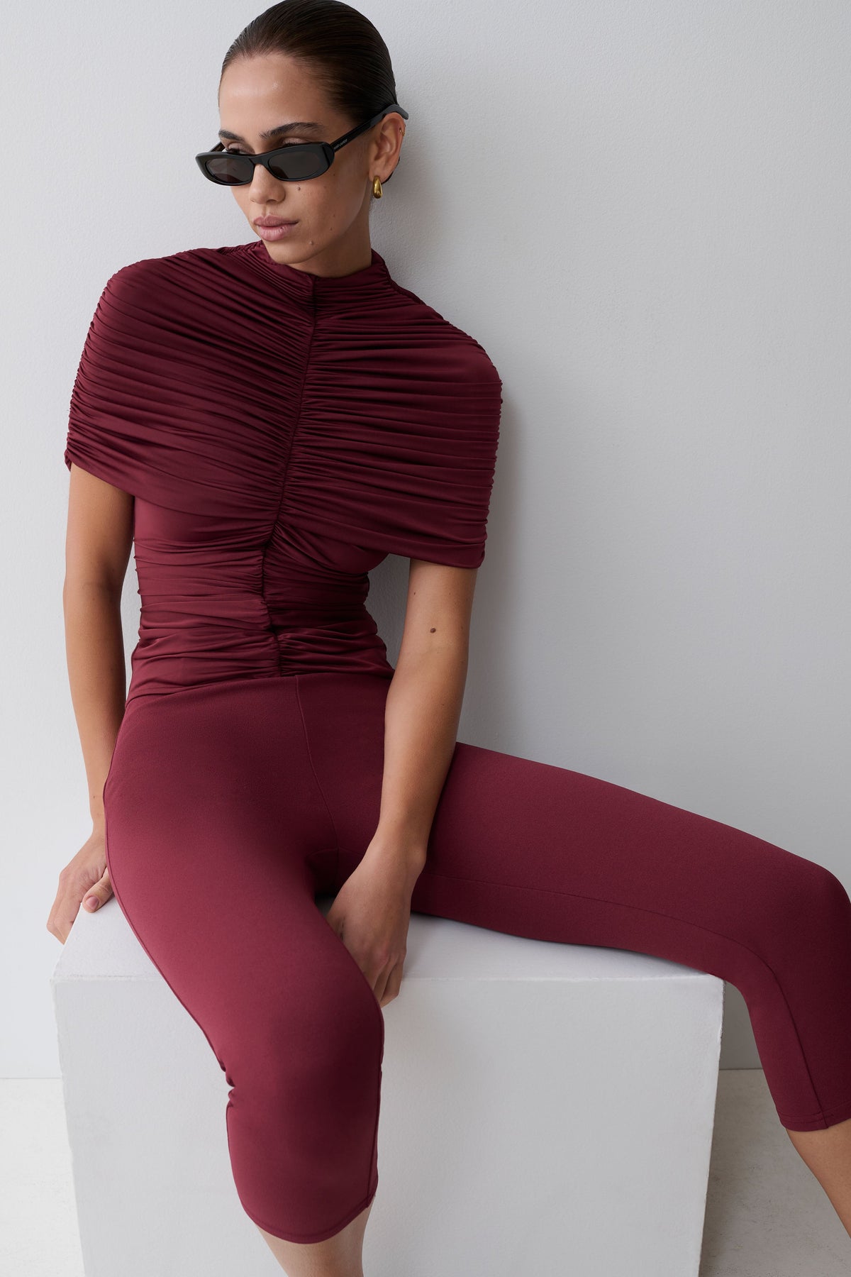 Woman wearing a burgundy outfit with matching capri pants.