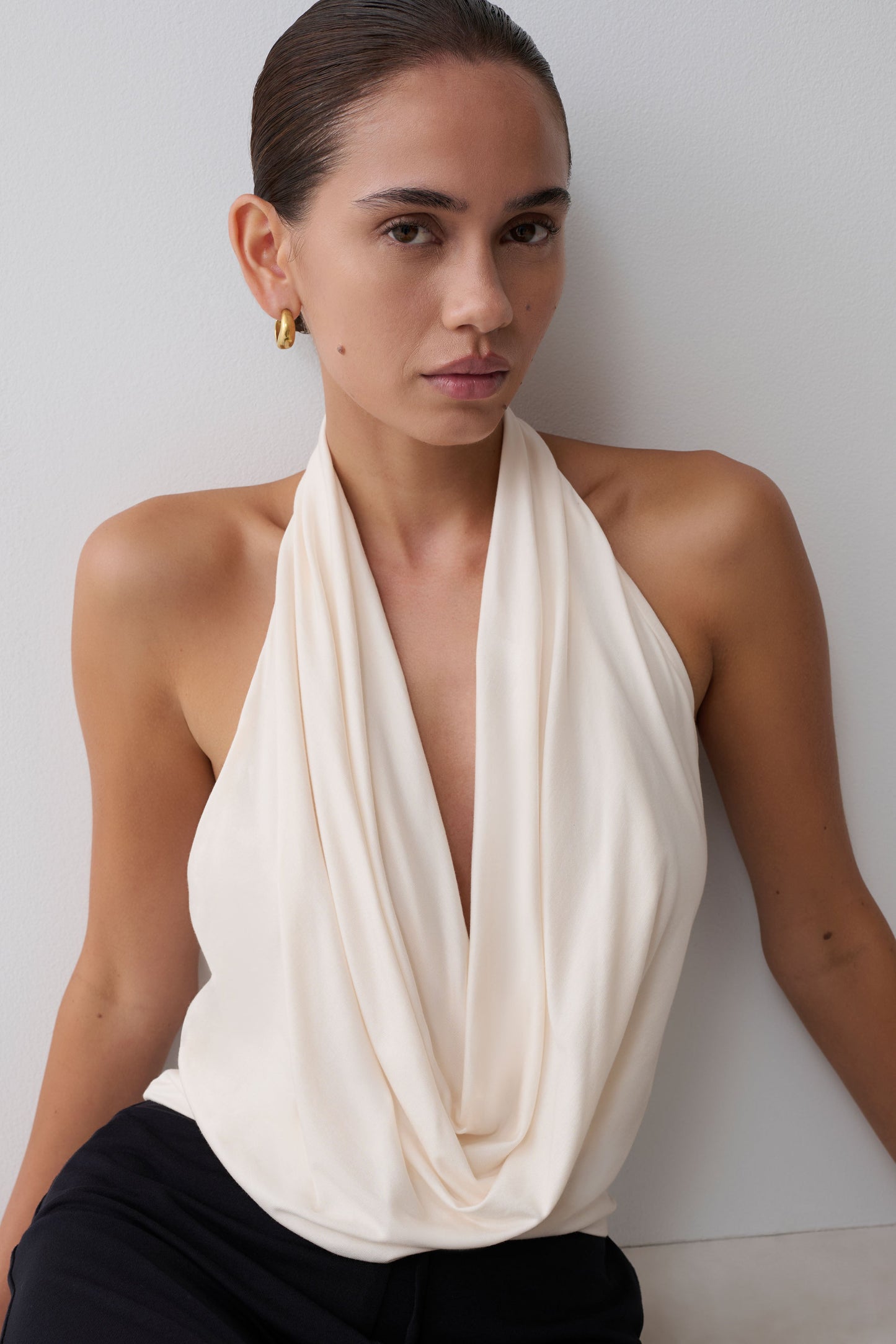 Woman wearing a white halter top against a plain background