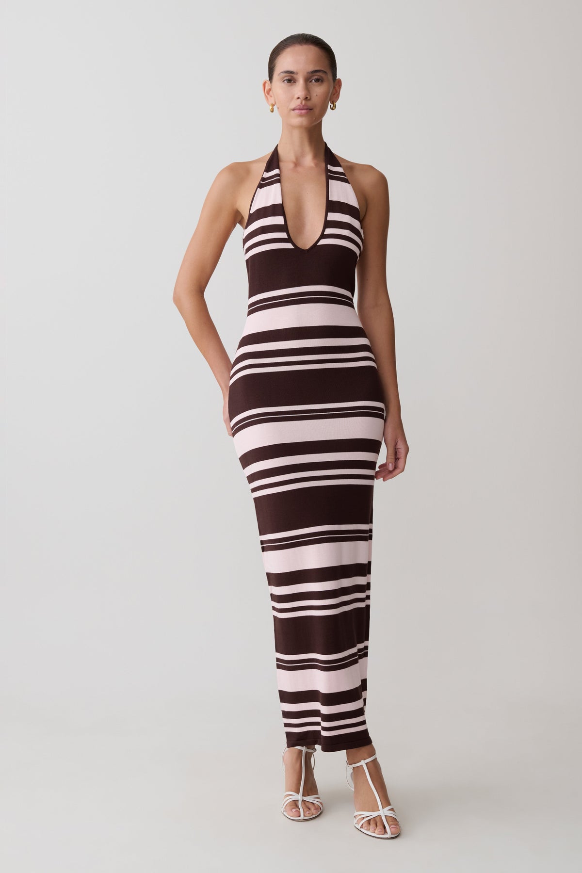 Woman wearing a brown and white striped dress on a plain background