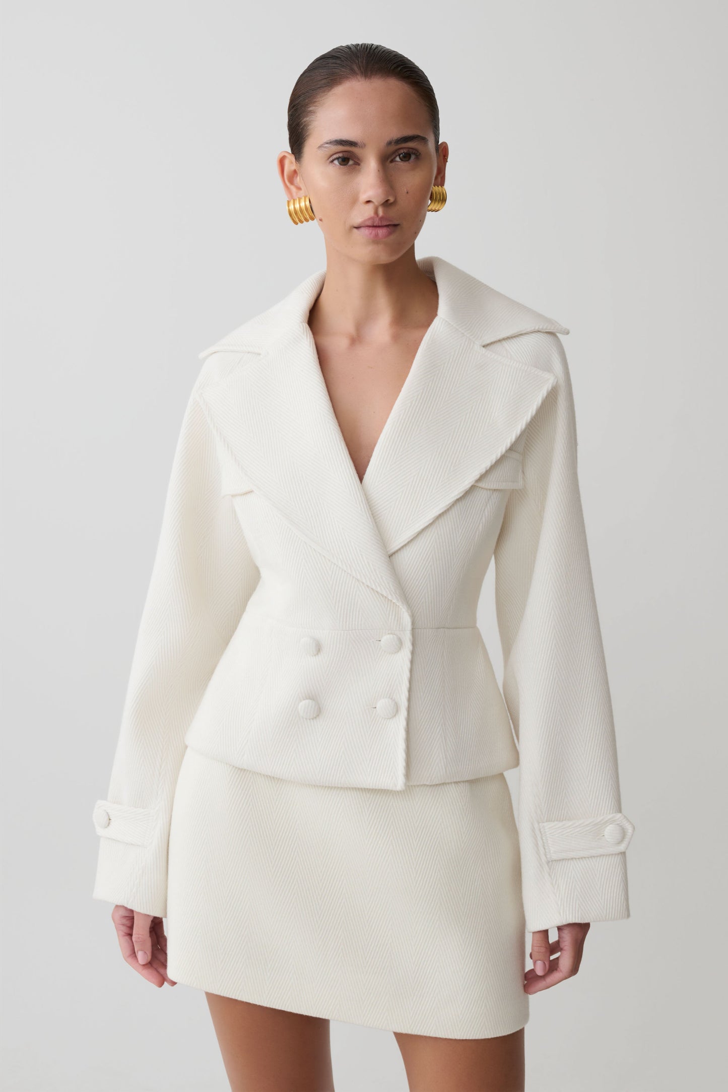 Woman wearing a white suit with a plain background