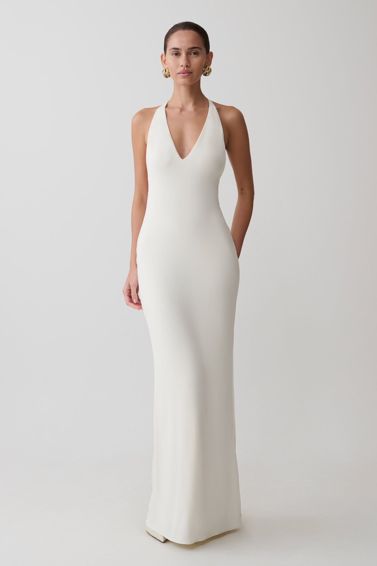 Woman wearing a white plunge neck maxi gown.