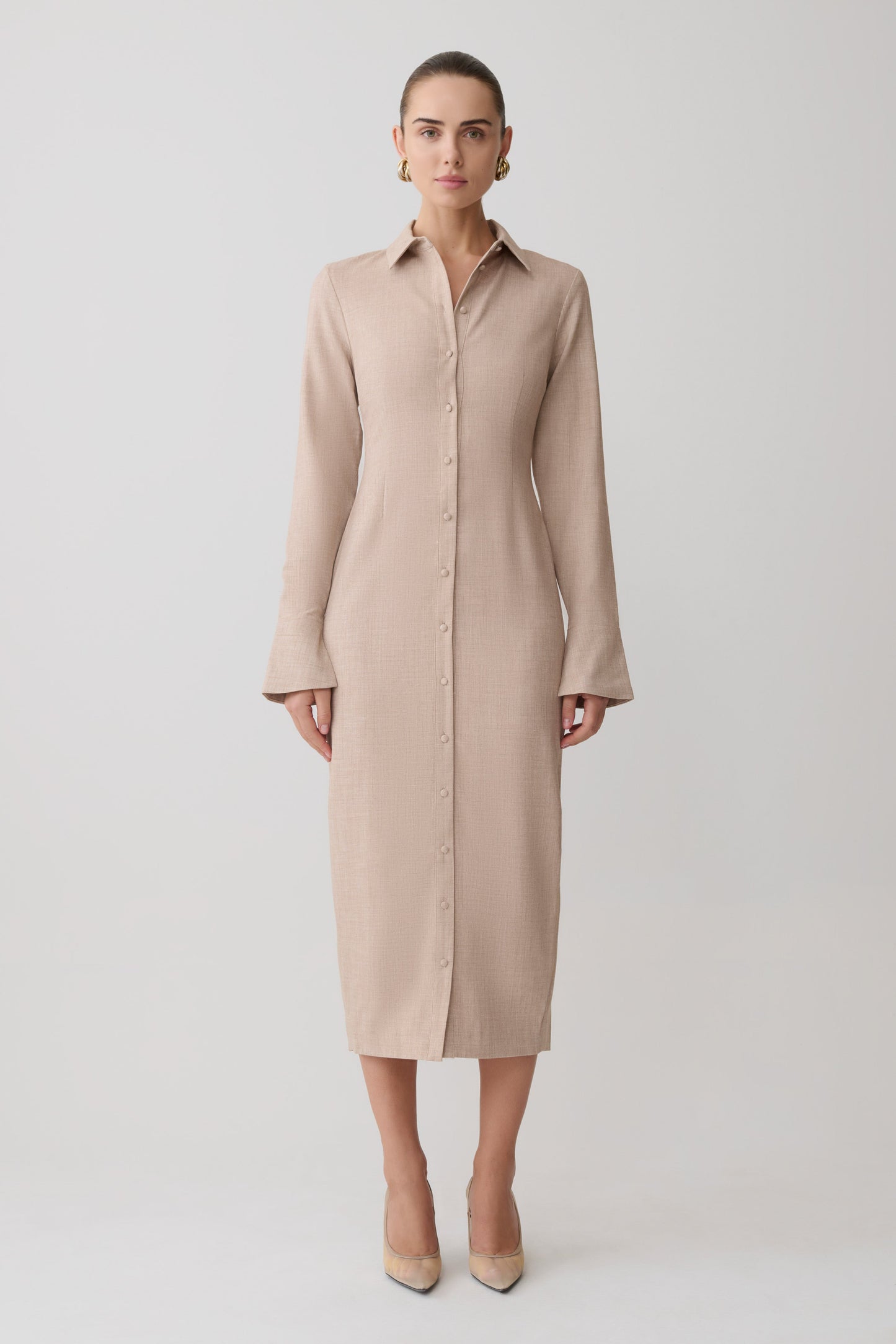 Woman wearing a beige long shirt dress on a white background