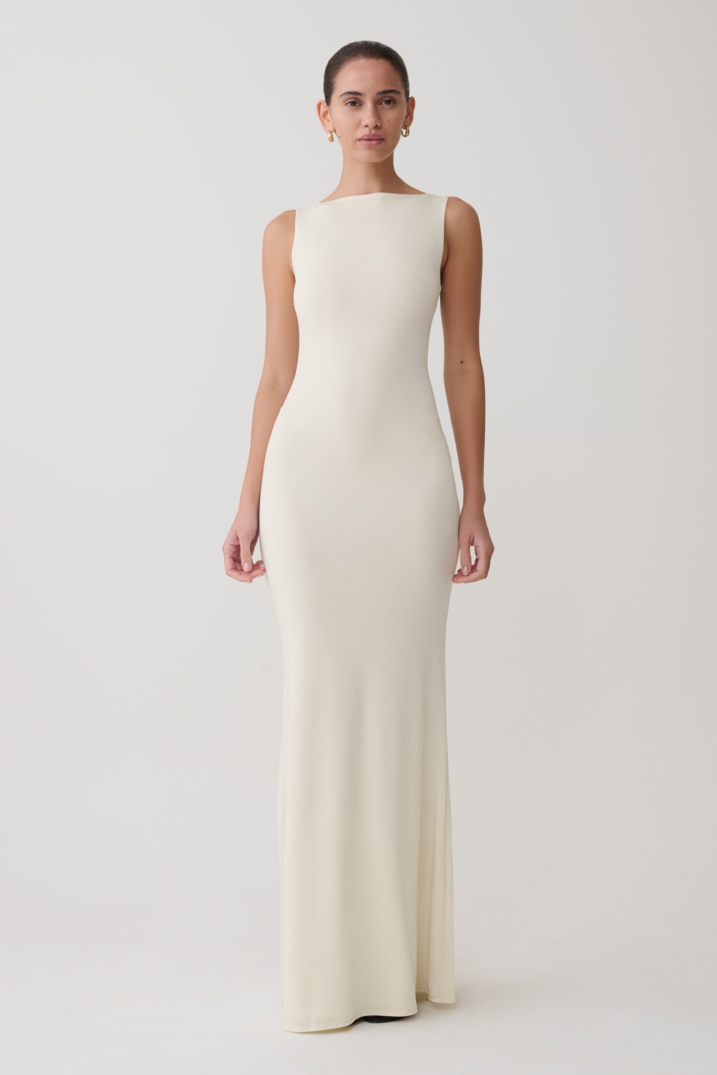 Woman wearing a long, off-white dress against a plain background