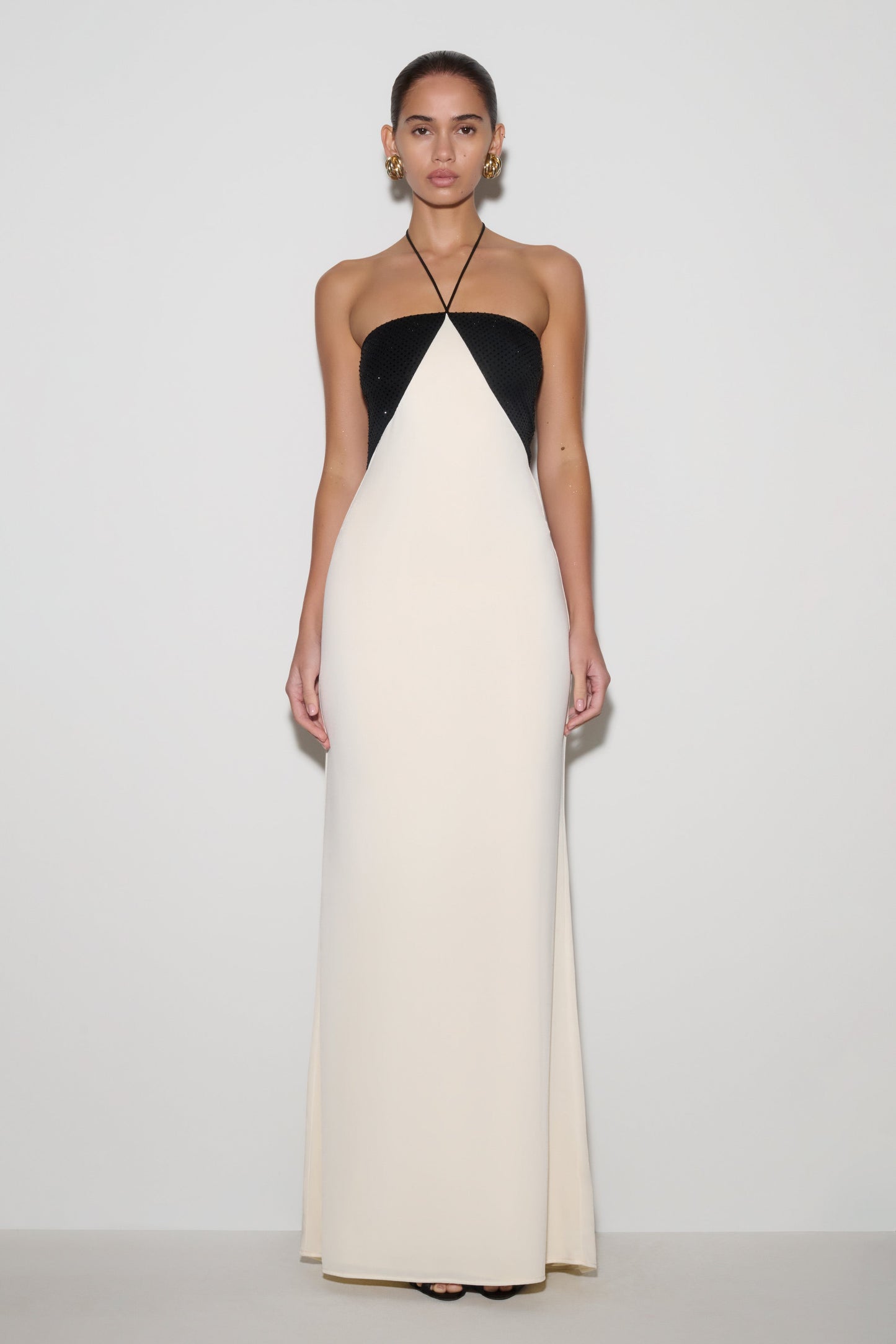 Woman wearing a black and white halter neck dress on a plain background