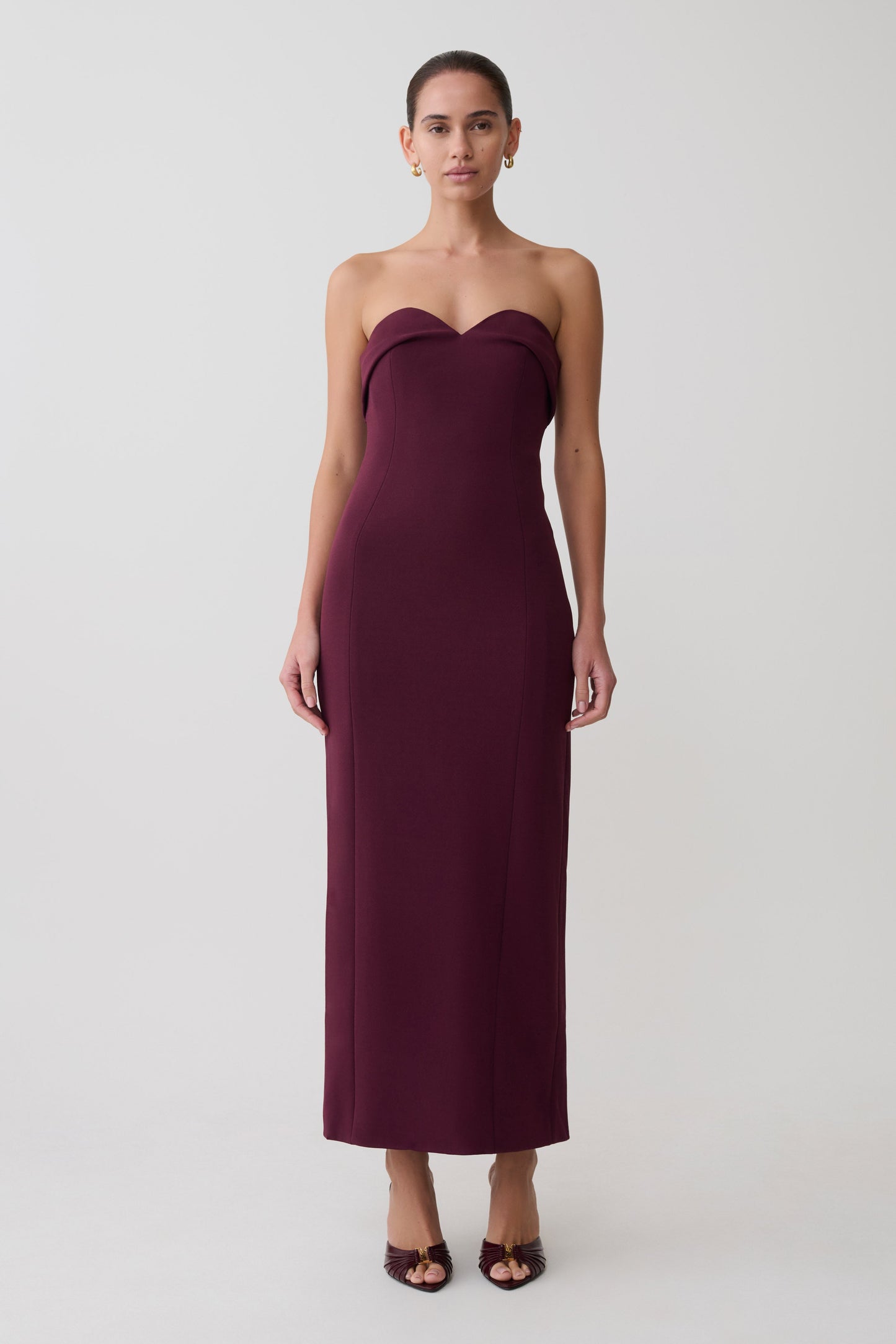 Woman wearing a strapless burgundy dress on a white background