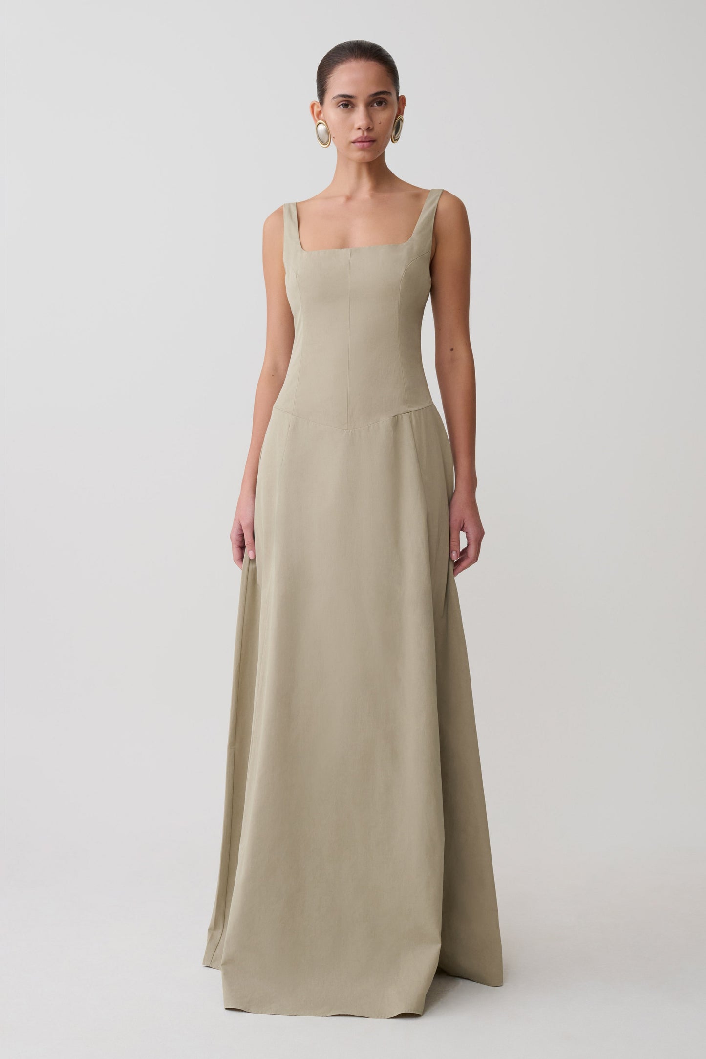 Woman wearing a beige sleeveless gown on a white background