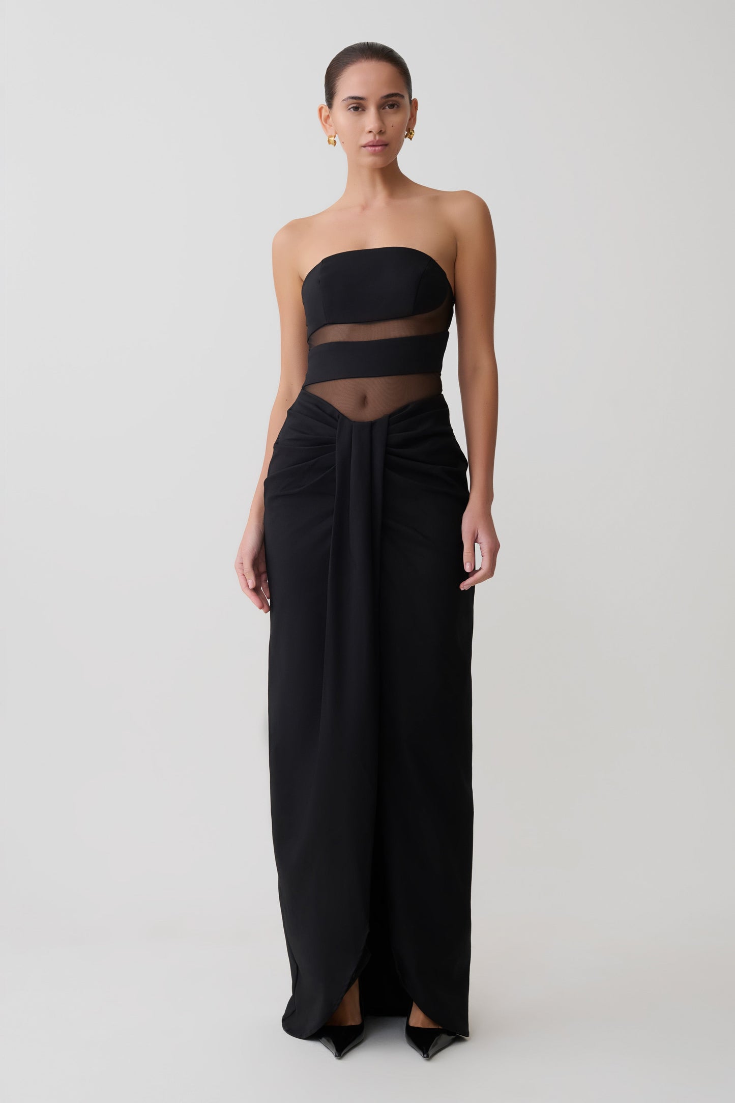 Black strapless gown with sheer panels on a white background