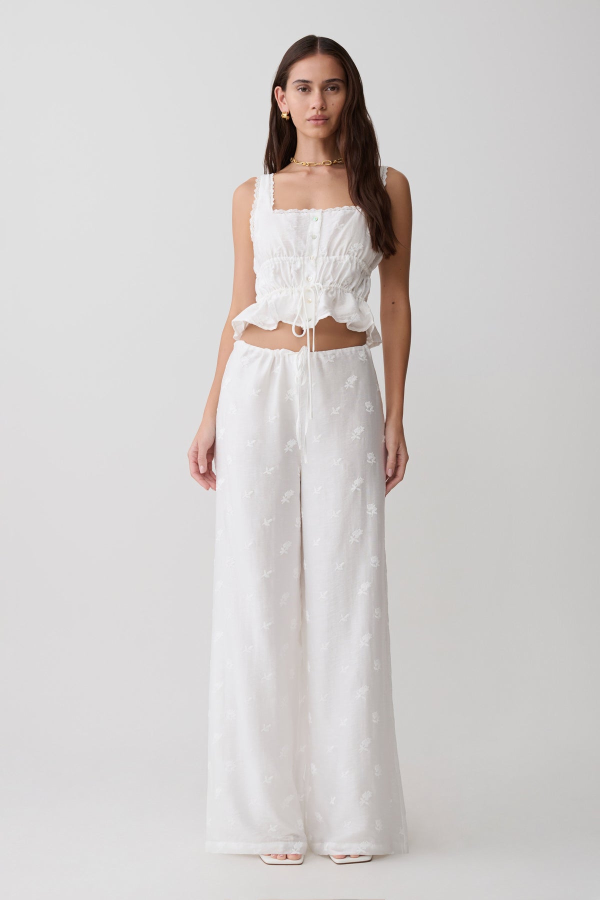Woman wearing a white embroidered top and tie pant set.