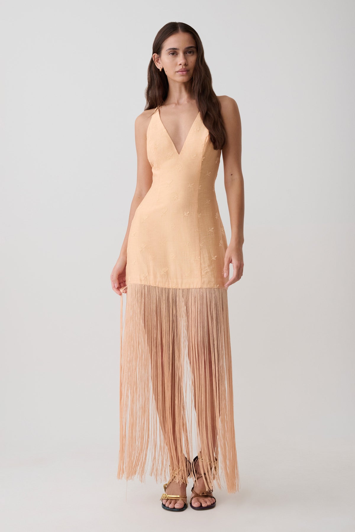 Woman wearing a v neck orange fringe maxi dress.