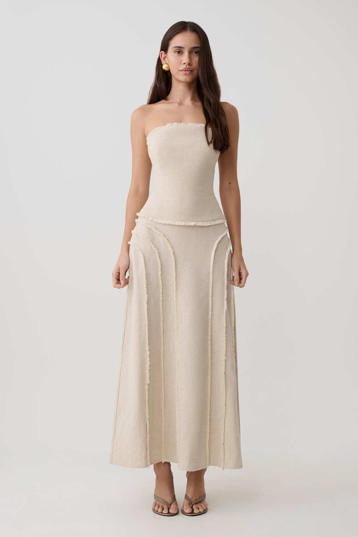 Woman wearing a frayed linen tube top with matching skirt set.