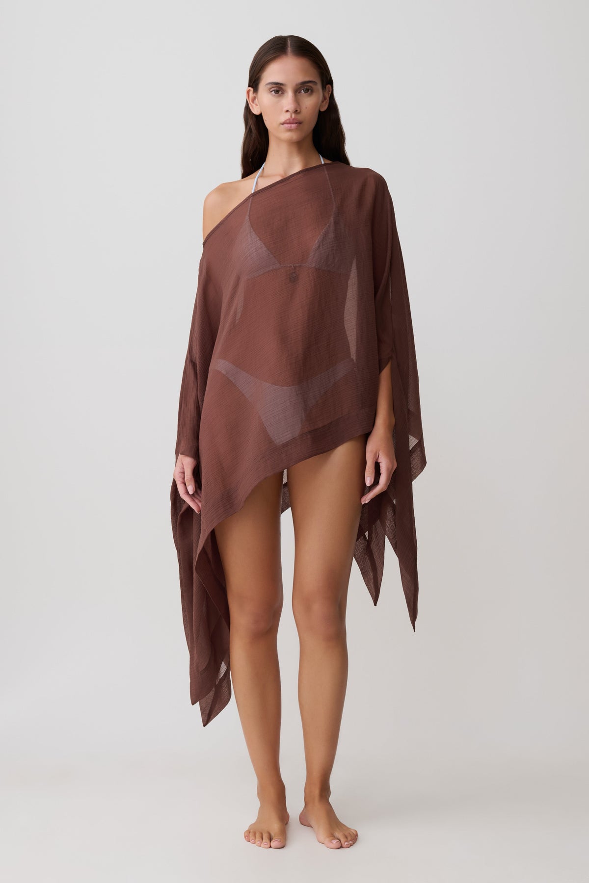 Woman wearing a sheer brown draped asymmetric top.