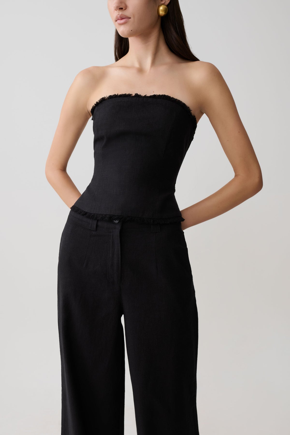 Woman wearing a black strapless tie back linen top.