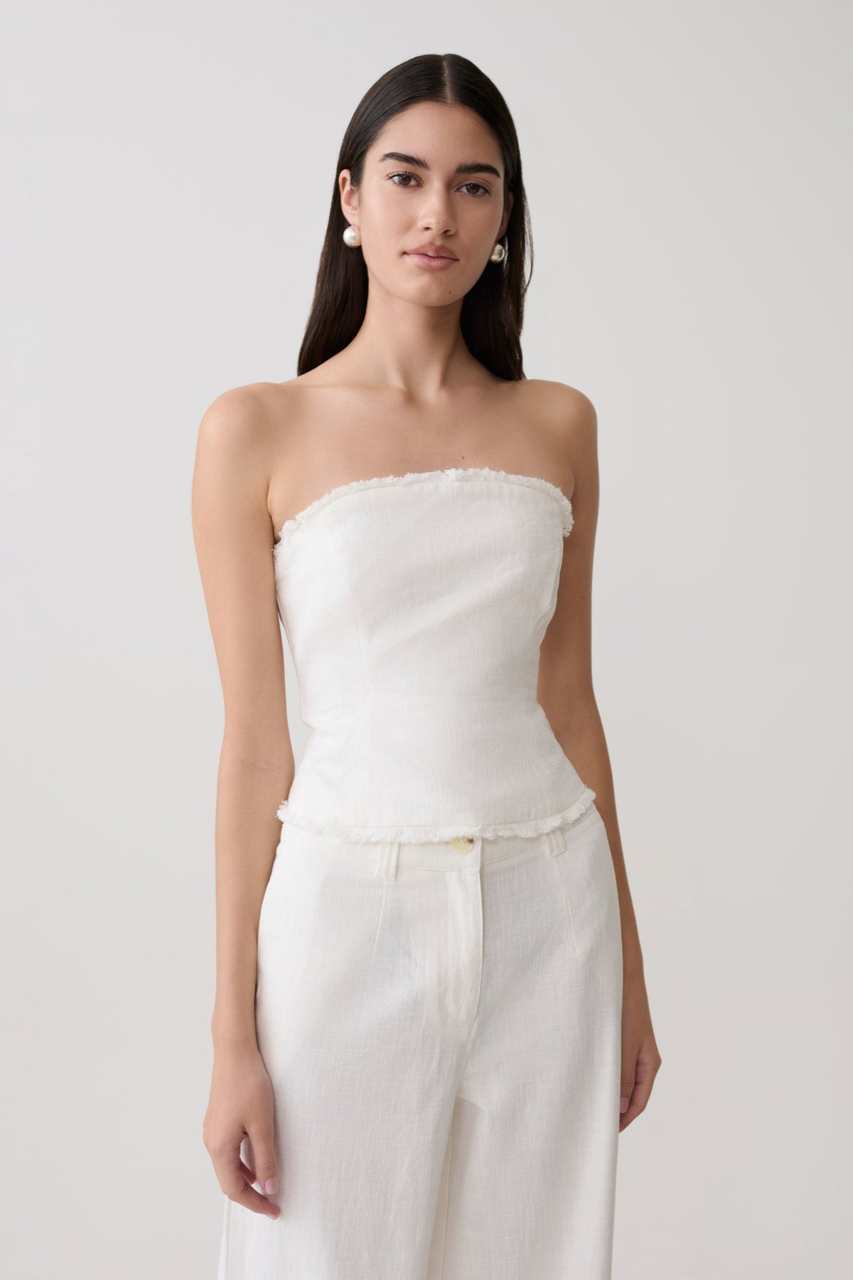 Woman wearing a white strapless tie back linen top.