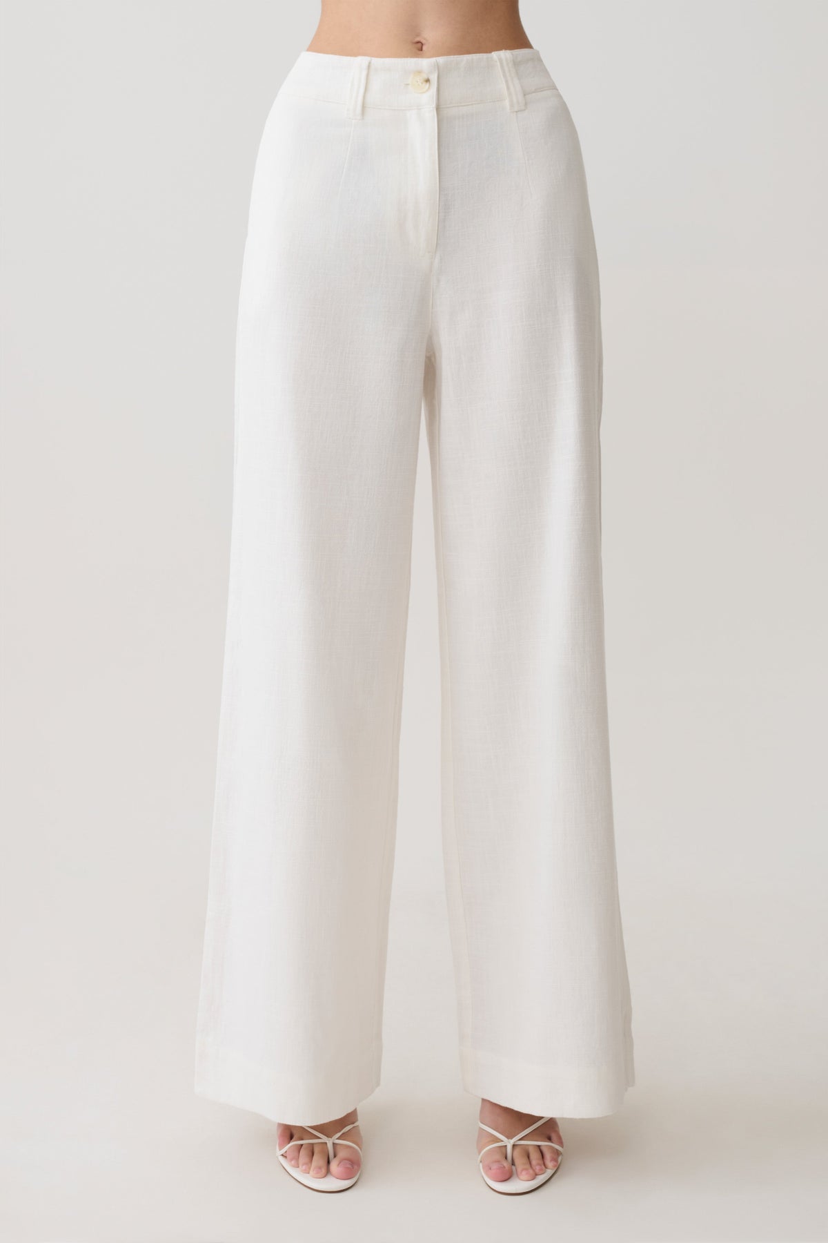 Woman wearing white straight leg linen pants.
