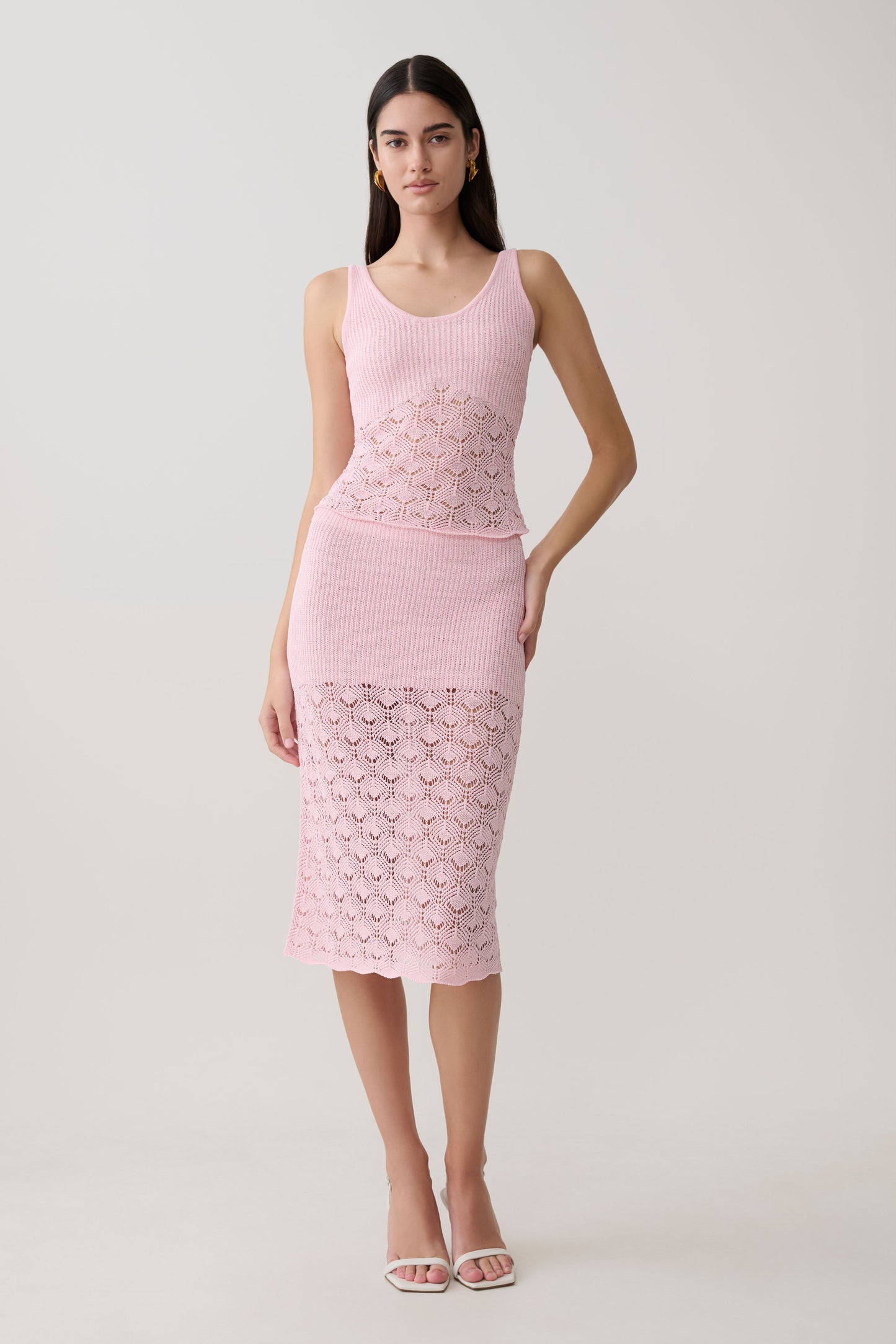 Woman wearing a pink sleevesless crochet top with matching skirt.