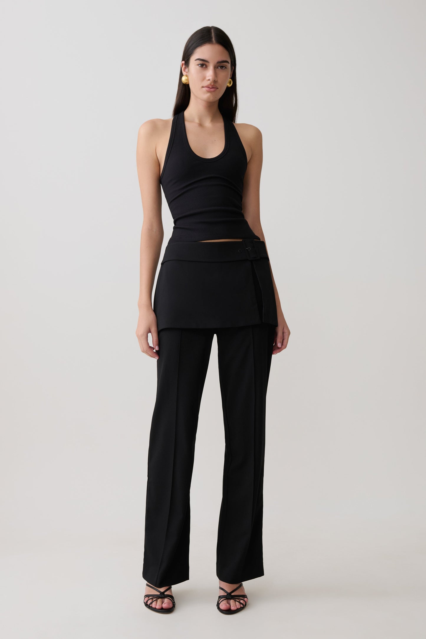 Woman wearing a black tank top with matching wrap skirt straight leg pants.