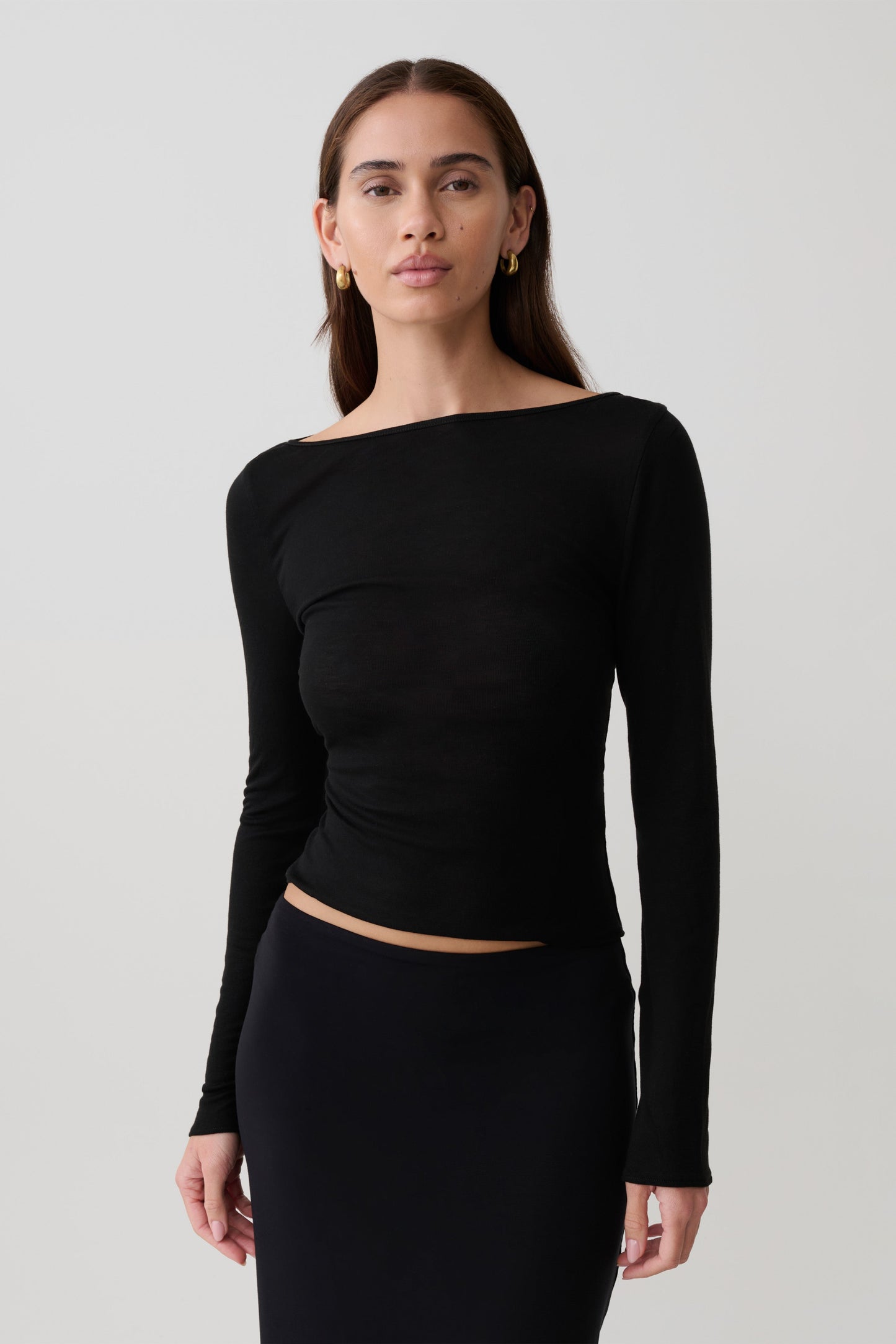 Woman wearing a black long-sleeve sheer top.