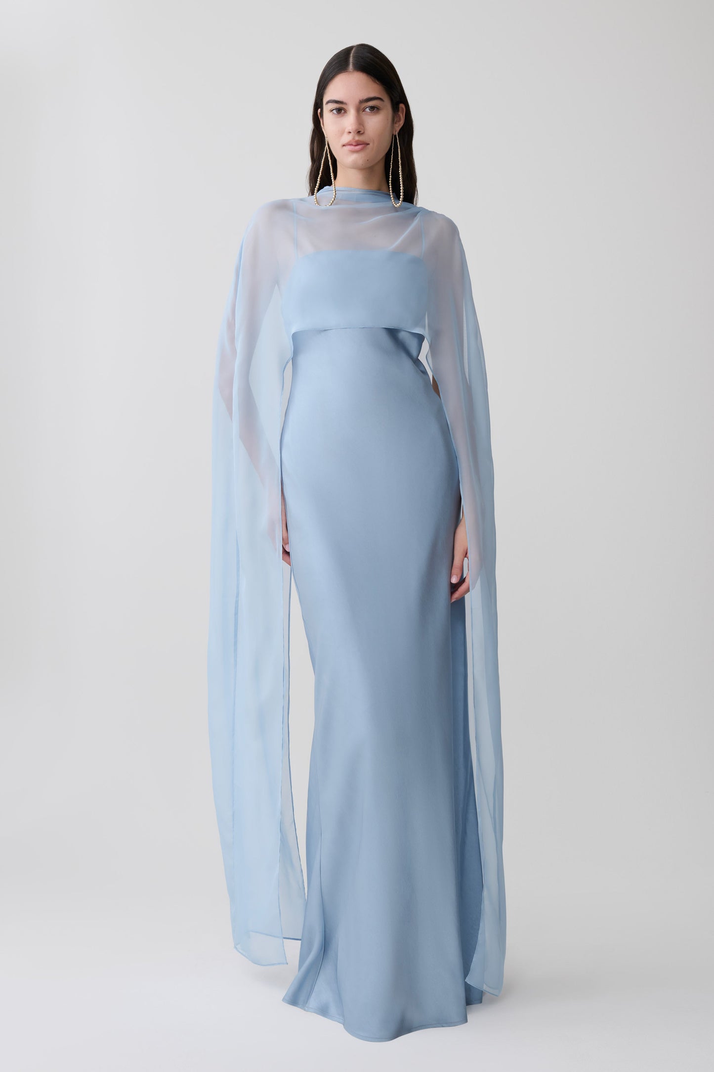 Woman wearing a light blue chiffon overlay maxi dress.