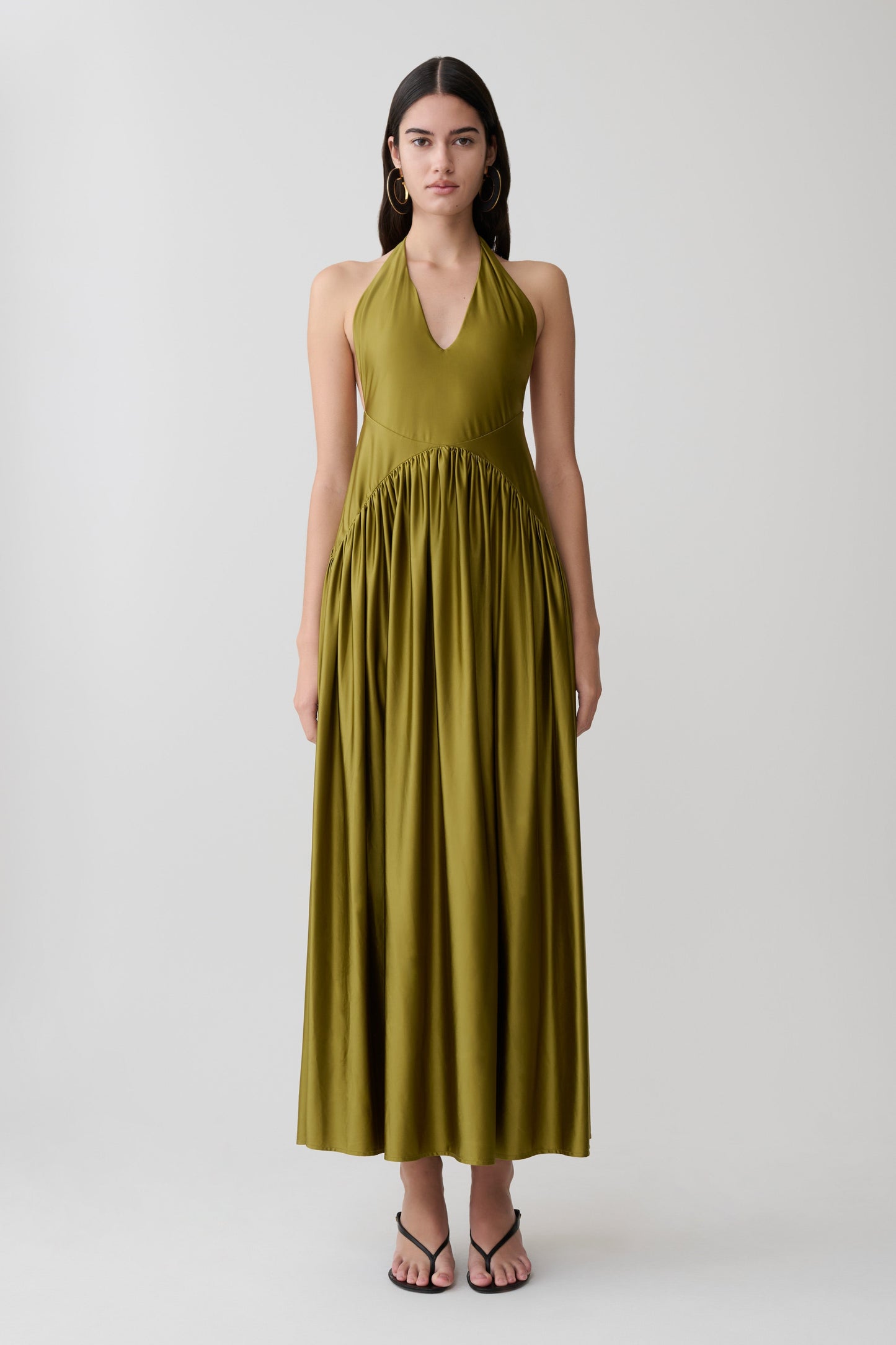 Woman wearing a green halter maxi dress.