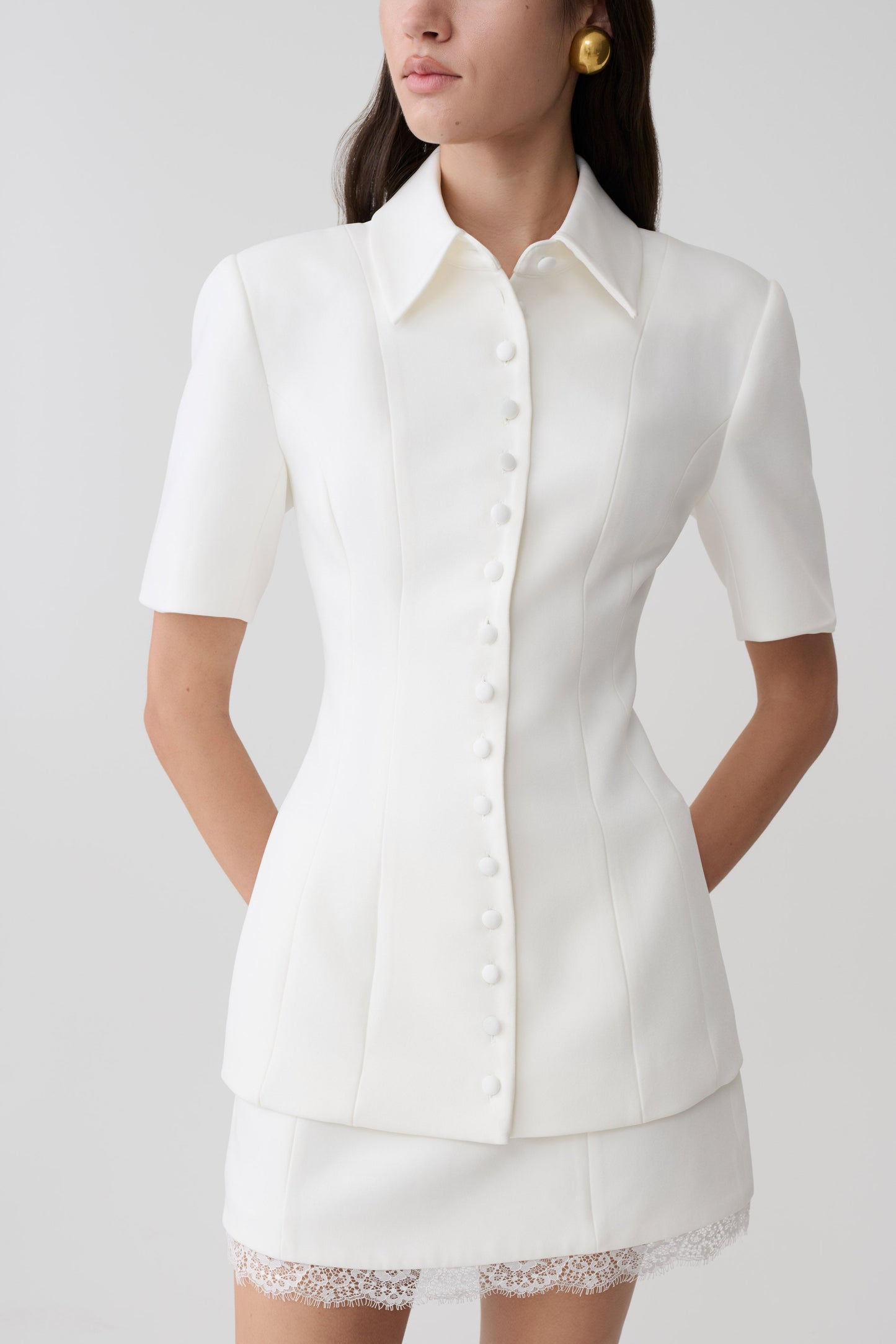 Woman wearing white button up short sleeved top.