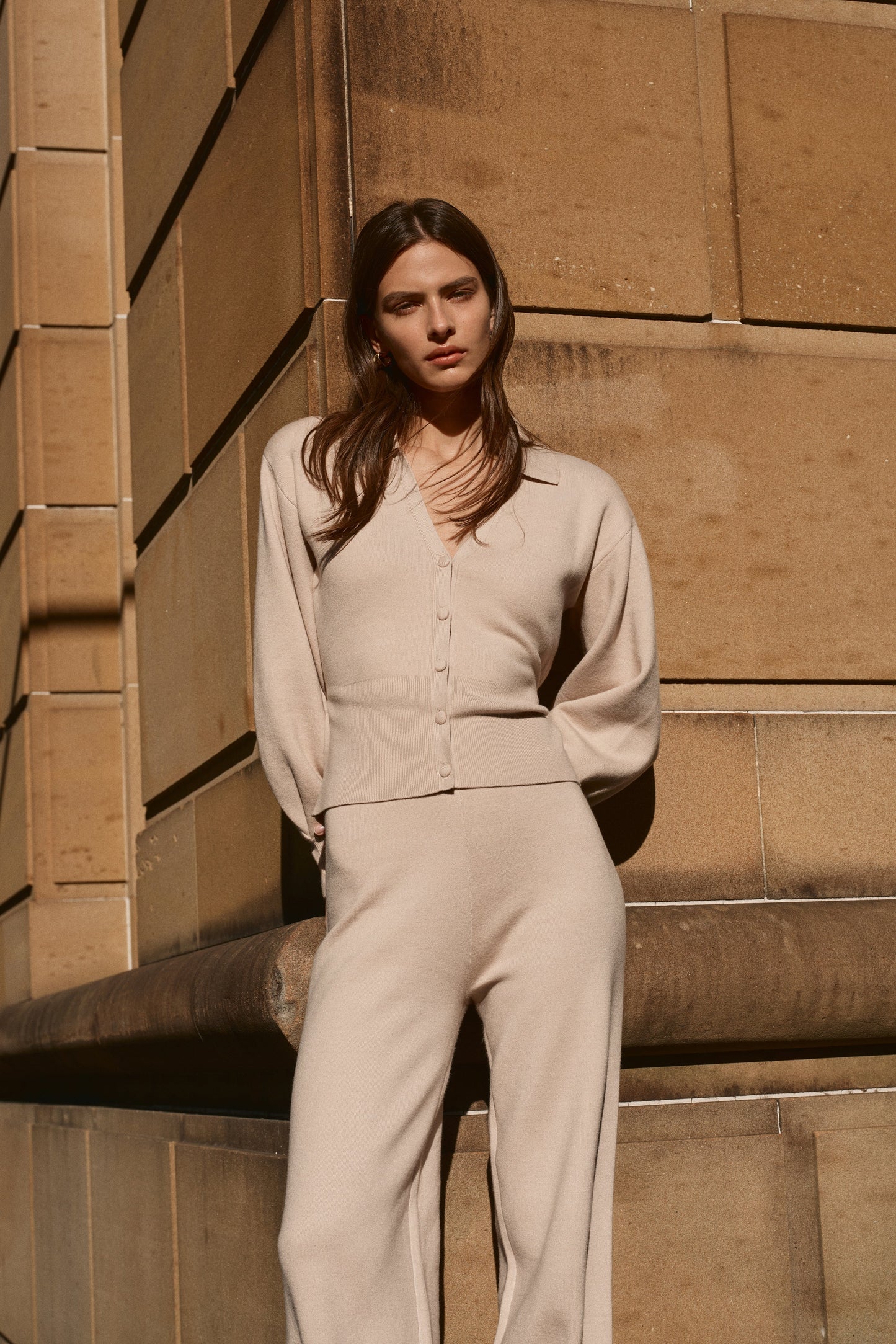 Woman wearing a beige knit blouson sleeve cardigan.