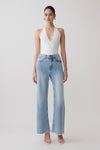 Woman wearing a white slinky halter bodysuit with blue jeans.