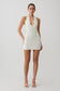 Woman wearing a white crochet halter mini dress.