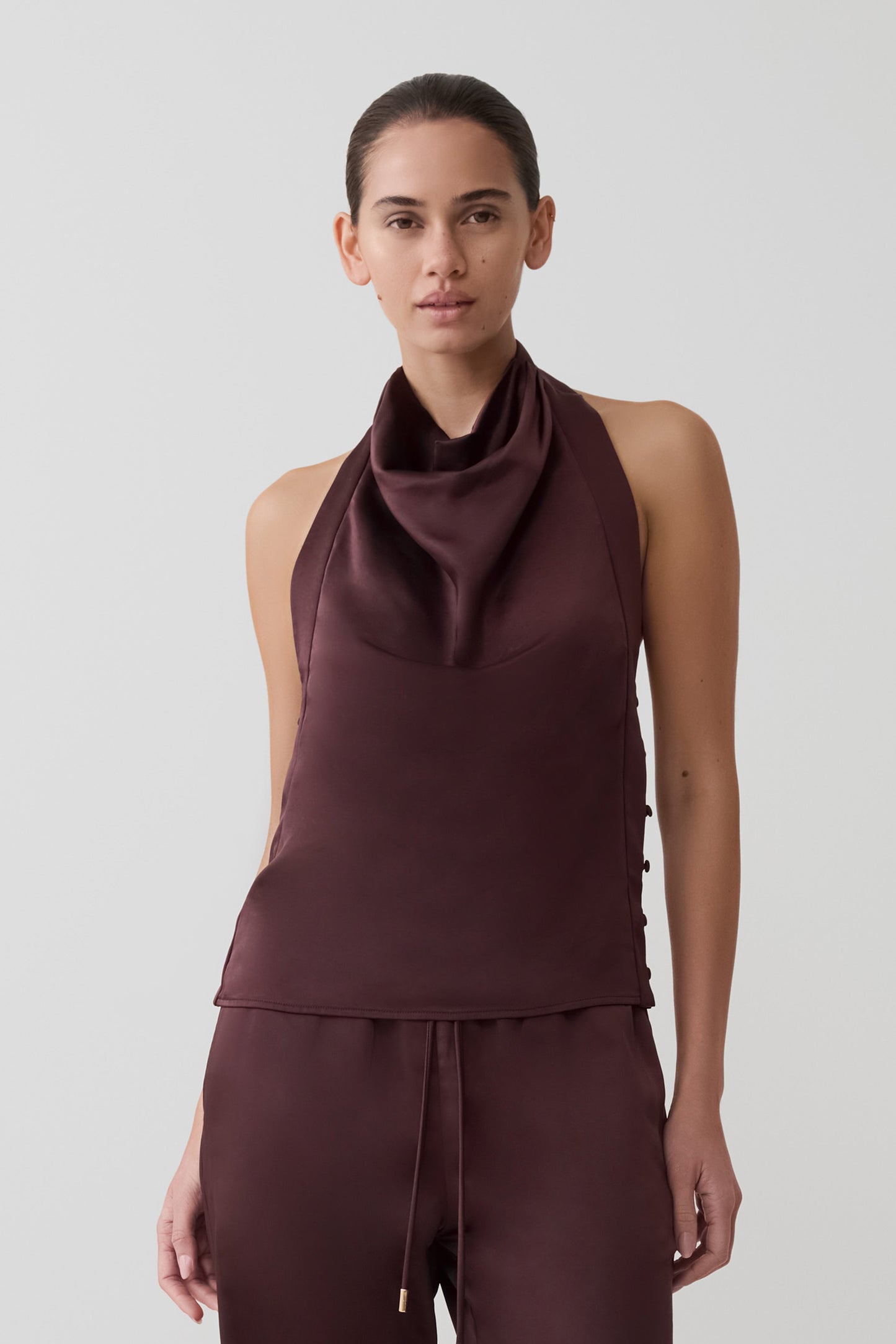 Woman wearing a brown satin halter sleeveless top.