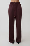 Woman wearing brown straight leg satin pants.