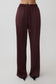 Woman wearing brown straight leg satin pants.