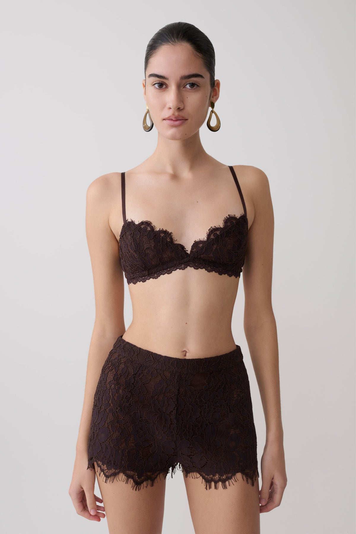 Woman wearing a dark brown lace bralette with matching lace shorts. 