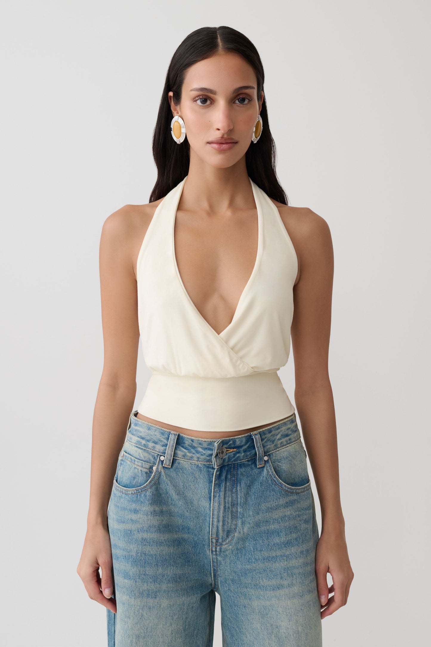 Woman wearing a white draped halter top.