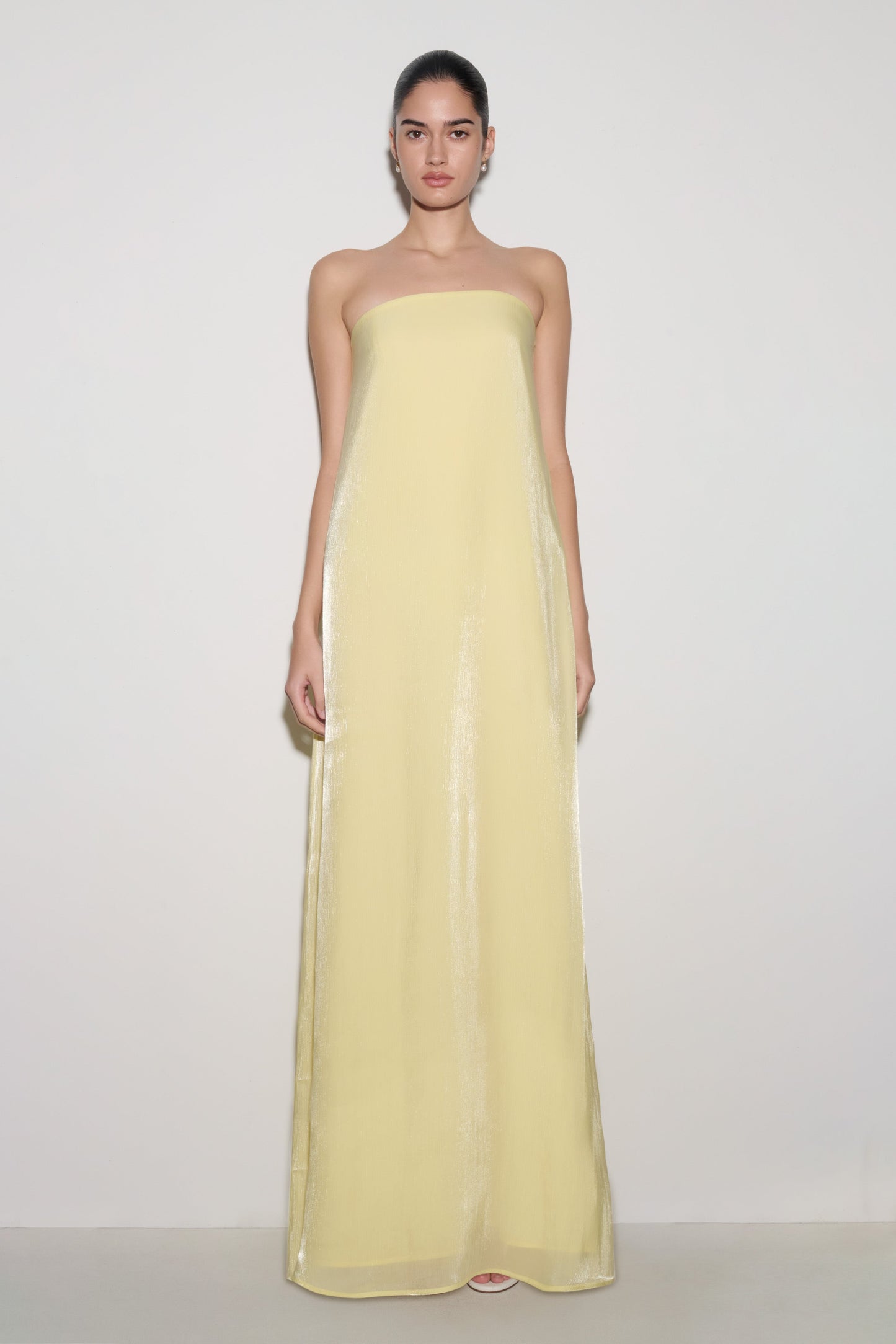 Woman wearing light yellow strapless maxi dress.
