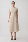 Woman wearing a beige linen cap sleeve midi dress.