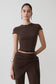 Woman wearing a brown high neck top with piping detail.